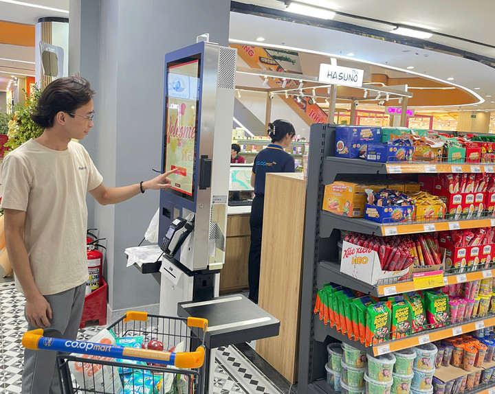 Khách hàng trải nghiệm hệ thống máy tính tiền tự động (Self-checkout).