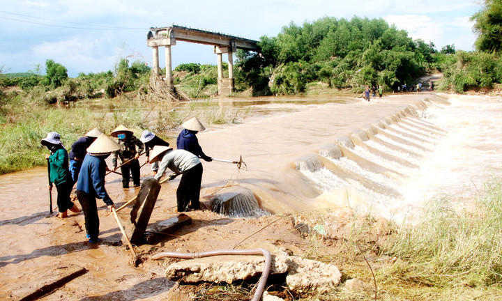 Sau lũ, người dân xã Yên Định lại tất bật ra ngầm dọn bùn đất, rác thải. Đằng xa là cây cầu Ao Giang bị lũ cuốn sập từ năm 2008.