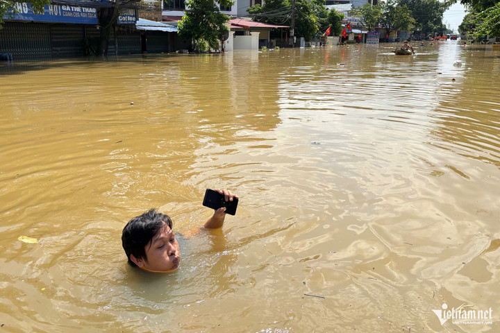 Người dân thôn Xuân Sơn chật vật trong dòng nước lũ.