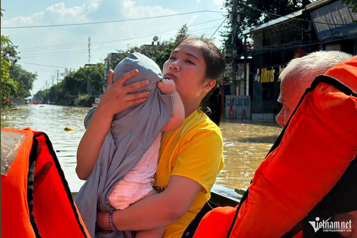 Chị Xuân bế con 8 tháng tuổi vượt lũ...