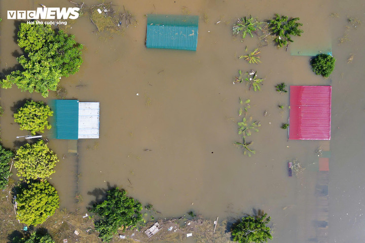 Đường xá biến mất dưới lớp nước đục ngầu, chỉ còn lác đác vài mái nhà lộ ra giữa không gian trắng xóa.