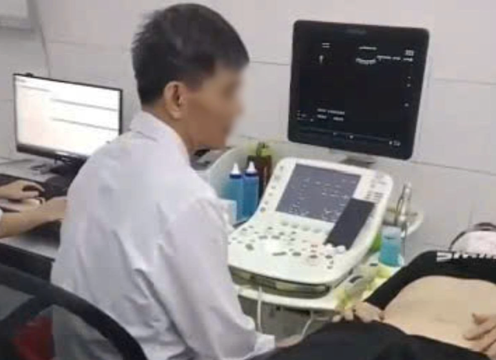 Hình ảnh bác sĩ được cho là vừa siêu âm vừa xem điện thoại. (Ảnh cắt từ clip)
