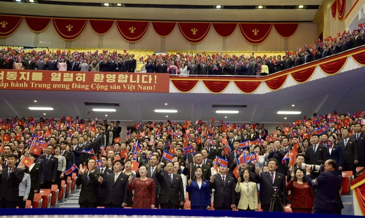 Ở hai bên khán đài là dòng chữ “Nhiệt liệt hoan nghênh đồng chí Tô Lâm, Tổng Bí thư ban Chấp hành Trung ương Đảng Cộng sản Việt Nam” và “Tình đoàn kết hữu nghị giữa nhân dân hai nước Triều Tiên và Việt Nam muôn năm”.