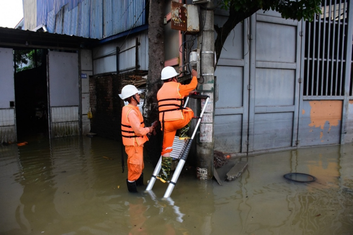 Công nhân EVNHANOI kiểm tra thiết bị điện tại khu vực ngập úng thuộc xã Trung Giã.