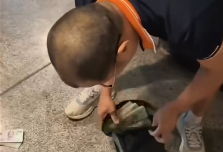 Người đàn ông nhặt các cọc tiền mệnh giá 500.000 dưới đất cho vào túi. (Ảnh cắt từ ciip)