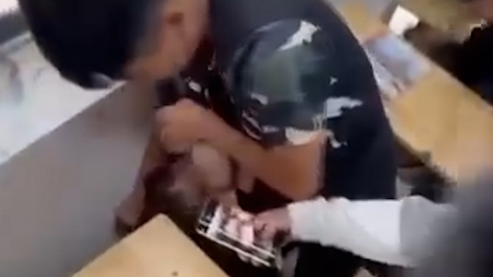 مرد طالب علم نے طالبہ کے بال پکڑے اور اس کا چہرہ کرسی سے دبا دیا۔ (تصویر کلپ سے کاٹی گئی)