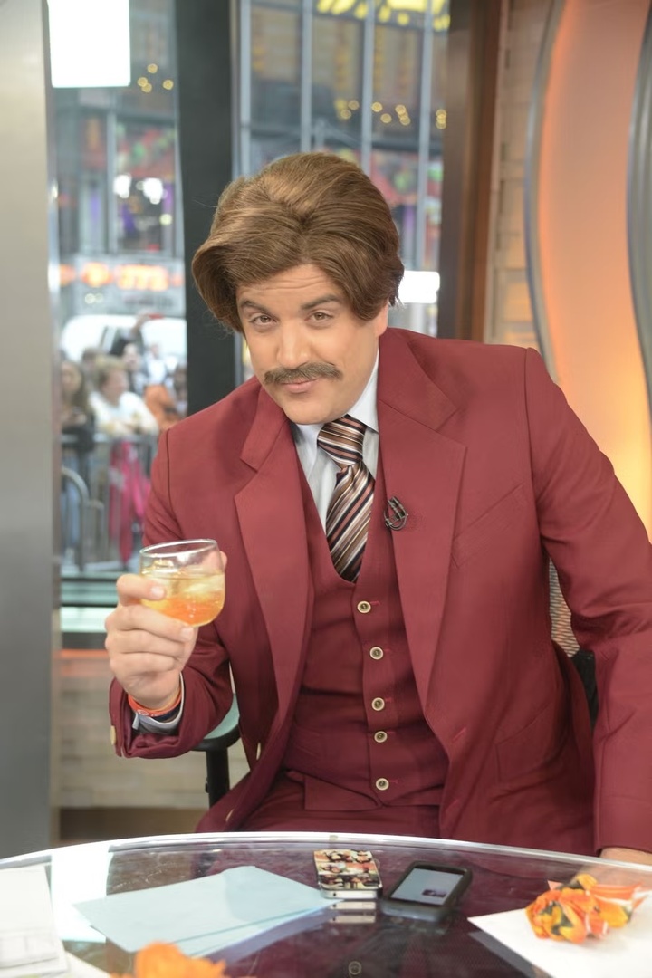 Lấy cảm hứng từ hình tượng Anchorman kinh điển, bạn có thể dễ dàng tạo nên diện mạo lịch lãm và hài hước. Hãy chọn bộ vest đỏ burgundy nổi bật, vuốt phồng mái tóc, tỉa gọn ria mép và cầm thêm ly whisky - chi tiết nhỏ nhưng đủ làm nên phong thái của một quý ông truyền hình thập niên 70.