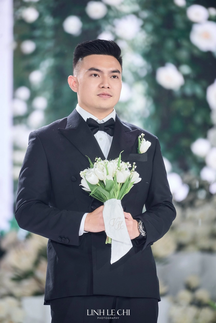 Chú rể Nguyễn Viết Vương xuất hiện với phong thái điềm đạm, tay cầm bó tulip trắng và chiếc khăn thêu lồng hai chữ cái đầu trong tên cô dâu, chú rể.