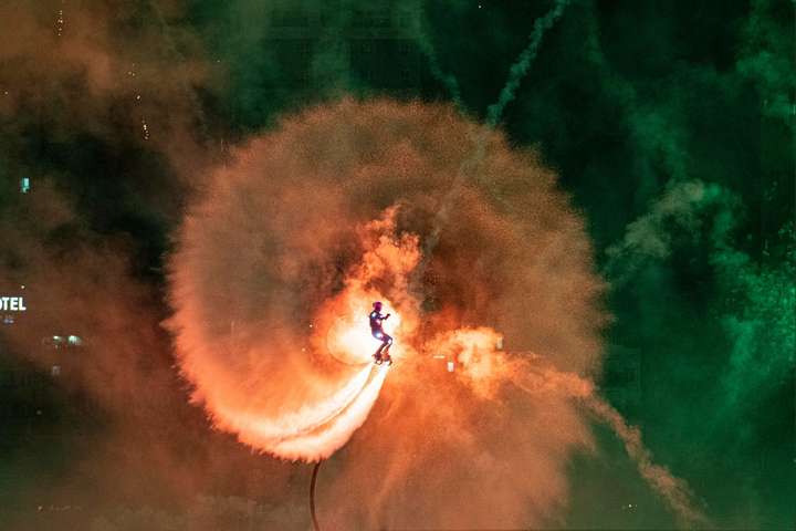 Vận động viên quốc tế trình diễn flyboard trên không với trang phục gắn đèn LED và hiệu ứng pháo sáng. (Ảnh: Sun Group)