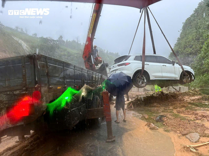 Lực lượng chức năng đang cẩu chiếc xe gặp nạn khỏi hiện trường vụ sạt lở ở cao tốc La Sơn - Tuý Loan