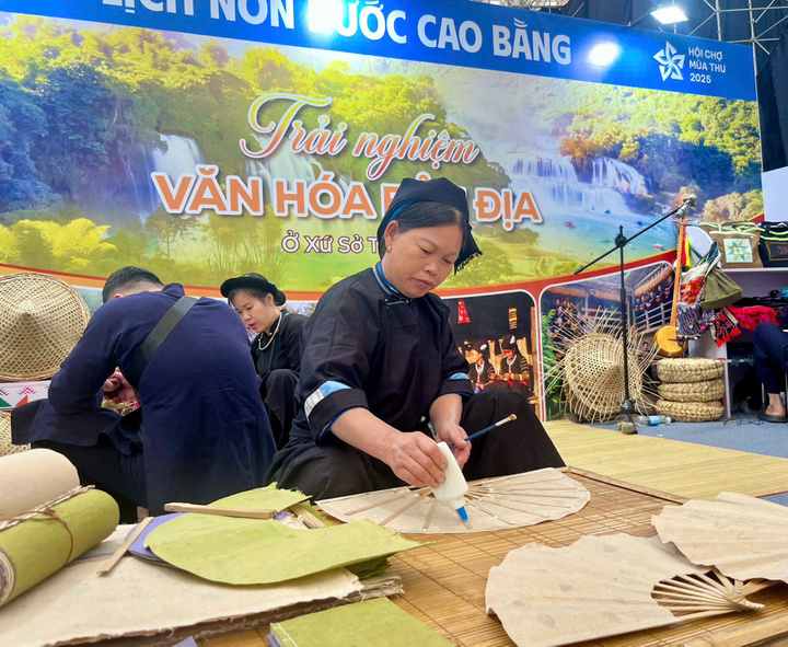 Nghệ nhân hướng dẫn người xem cách làm quạt giấy truyền thống. (Ảnh: Hoàng Dung).