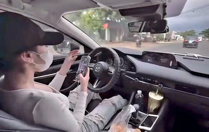 Cô gái buông 2 tay bấm điện thoại (ảnh cắt từ clip)