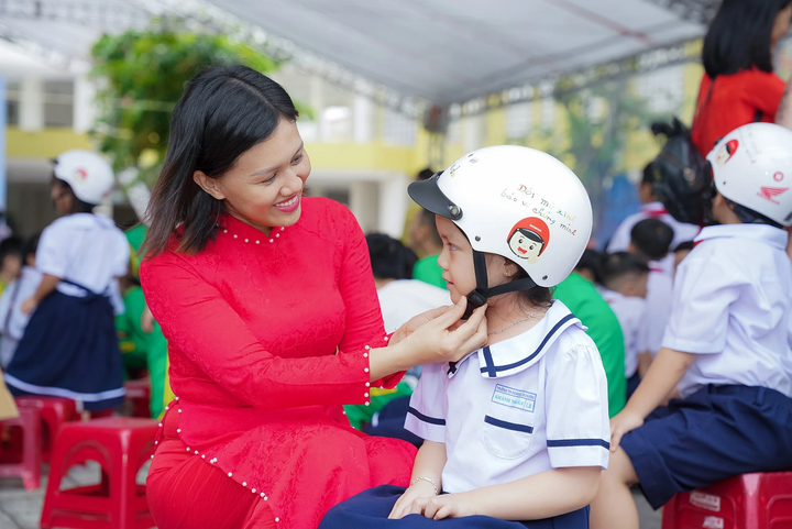 Giáo viên hướng dẫn học sinh đội mũ bảo hiểm đúng cách.