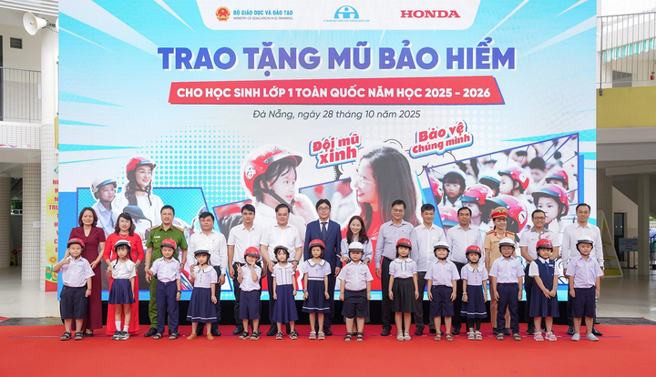 Các đại biểu trao tặng mũ bảo hiểm cho các em học sinh lớp 1 trường Tiểu học Hoàng Dư Khương.