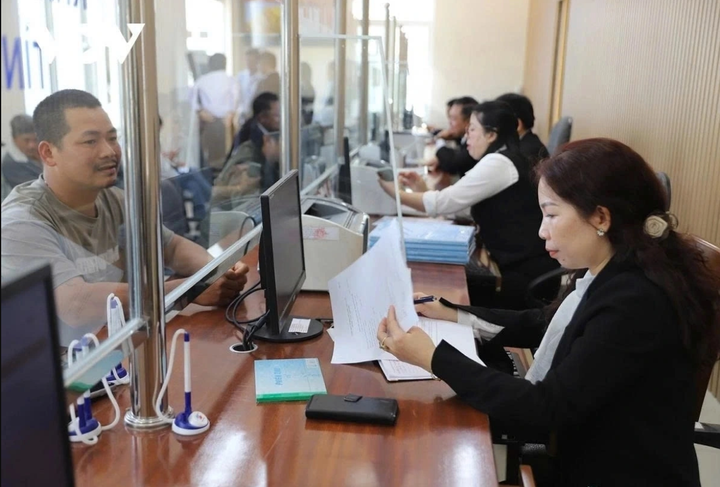 Công chức giải quyết thủ tục hành chính cho người dân trong ngày đầu vận hành chính thức chính quyền địa phương 2 cấp.