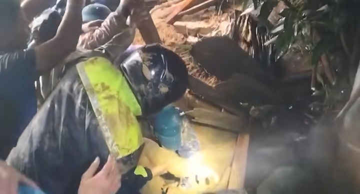 Lực lượng chức năng bới trong lớp bùn đất để đưa nạn nhân ra ngoài.