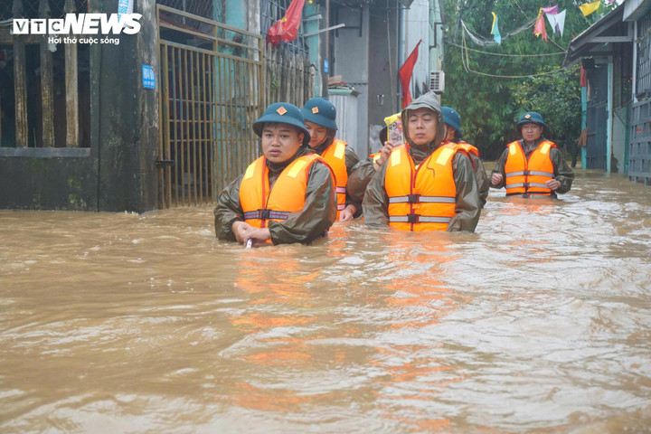 Lực lượng chức năng dầm mình trong nước lũ để di chuyển đến các khu vực ngập sâu, triển khai công tác sơ tán dân.