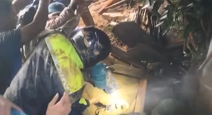 Lực lượng chức năng bới trong lớp bùn đất để đưa nạn nhân ra ngoài.