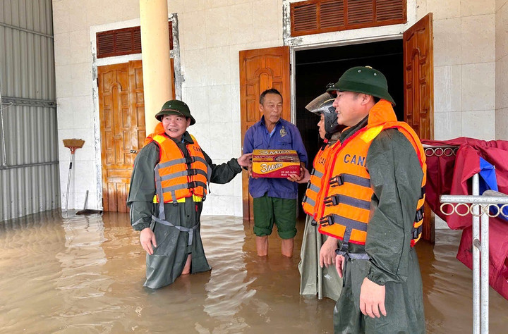 Lực lượng chức năng phát nhu yếu phẩm cho người dân vùng bị ngập lụt. (Ảnh T.T)