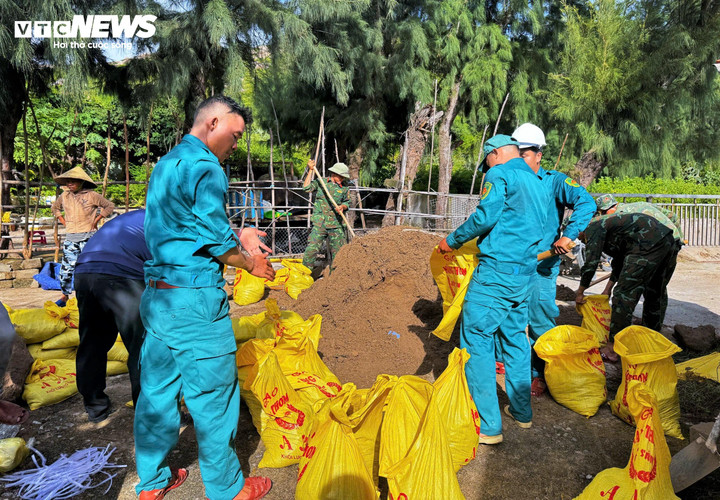 Lực lượng dân quân tự vệ trên đảo hỗ trợ người dân tải bao cát chằn chống, giằn néo nhà cửa.