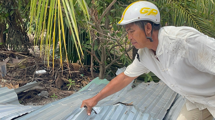 Ông Bình thu gom mái tôn do bão số 13 thổi bay.