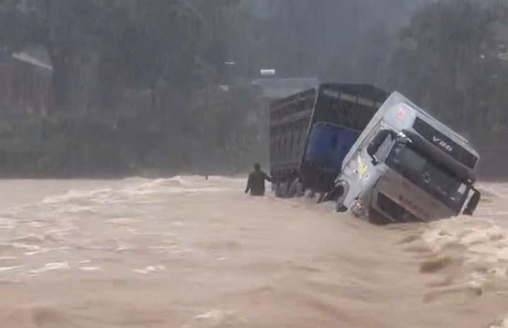 Tài xế xe đầu kéo cố tình băng qua cầu tràn đang bị ngập và bị dòng nước lũ cuốn đang đứng chờ cứu hộ. (Ảnh: CTV)