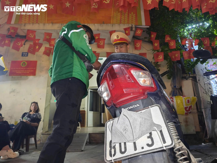 Cảnh sát giao thông xử lý vi phạm che - dán biển số xe máy. (Ảnh: Minh Tuệ)