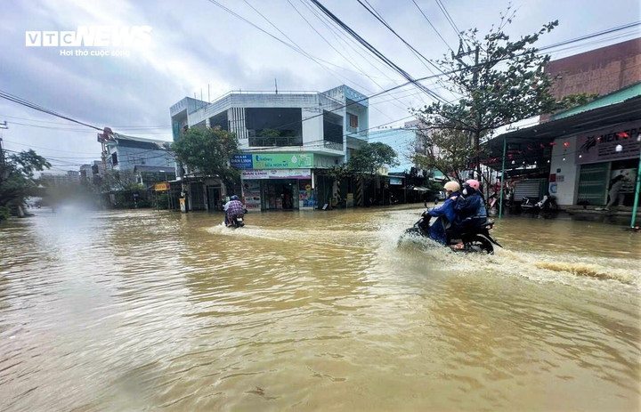 Người dân di chuyển trên tuyến đường khu chợ Dinh trong tình trạng nước ngập hơn nửa bánh xe.