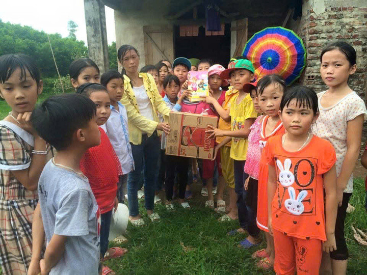 السيدة ثو (ذات السترة الصفراء) تعطي المعكرونة الفورية والكتب كهدايا للطالب تشيو جي لينه (ذات القبعة الوردية، وتحمل كتابًا).