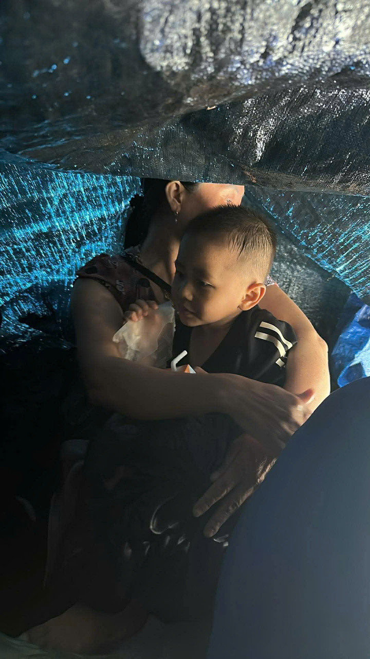 Một em bé co ro trên mái nhà giữa cơn lũ.