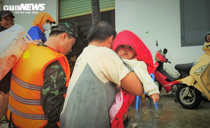 Ánh mắt của một em bé ngây thơ trong vòng tay bảo vệ của bố khi được lực lượng chức năng cứu hộ an toàn.