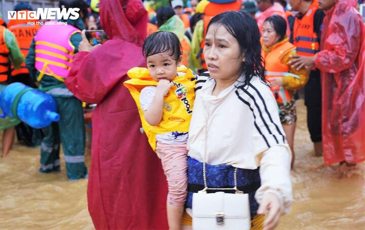 Người mẹ bế con gái nhỏ vào lều dã chiến sau một đêm chịu đựng mưa gió.