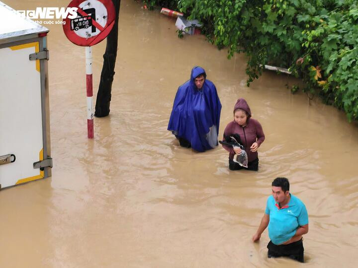 Người dân bì bõm lội giữa dòng nước lũ trong sáng nay.