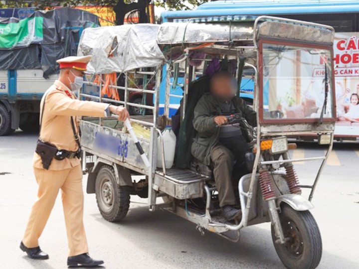 Lực lượng chức năng xử lý một tài xế xe ba bánh không bảo đảm các điều kiện an toàn để tham gia giao thông. (Ảnh: Ngọc Tiến)