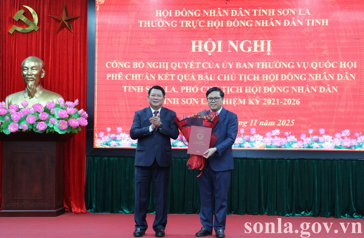 Ông Lò Minh Hùng - Chủ tịch HĐND tỉnh Sơn La trao nghị quyết và tặng hoa chúc mừng tân Phó Chủ tịch HĐND tỉnh Sơn La Nguyễn Việt Cường. (Ảnh: Lê Hồng)