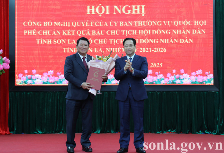 Bí thư Tỉnh ủy Sơn La Hoàng Văn Nghiệm trao nghị quyết và tặng hoa chúc mừng ông Lò Minh Hùng - Chủ tịch HĐND tỉnh Sơn La khóa XV. (Ảnh: Lê Hồng)