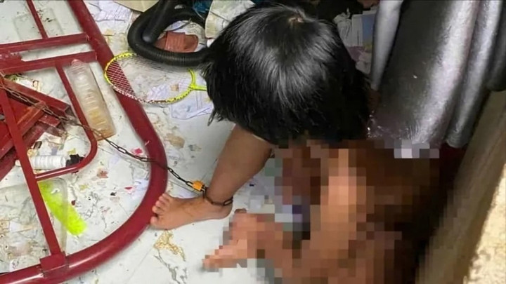 Bé gái bị cha xích chân trong căn phòng bừa bộn.