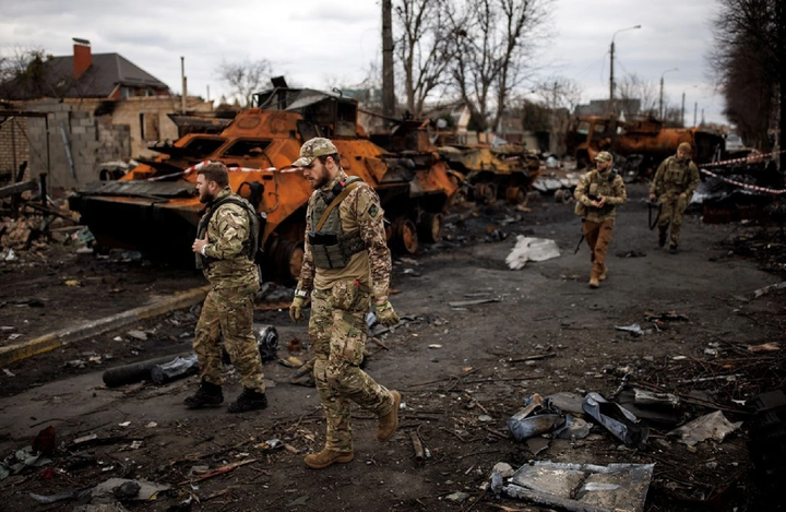 Binh lính Ukraine di chuyển cạnh xác xe tăng ở Bucha. (Ảnh: Reuters)