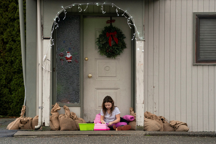 Mia Rentz-Goudelock, 9 tuổi, ngồi cạnh những bao cát chống lũ tại Burlington, bang Washington, Mỹ, ngày 12/12/2025. (Ảnh: Reuters/David Ryder)