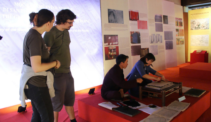 Du khách chăm chú tìm hiểu mộc bản chùa Vĩnh Nghiêm tại triển lãm thành tựu “Di sản ngàn năm Yên Tử - Vĩnh Nghiêm - Côn Sơn, Kiếp Bạc”.