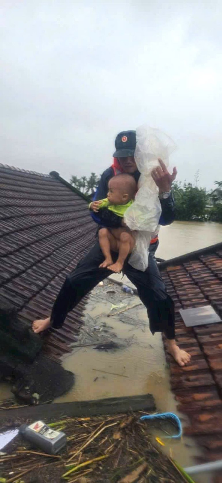 Hình ảnh Thiếu tá Khiên bế em bé đứng trên mái nhà gây xúc động.