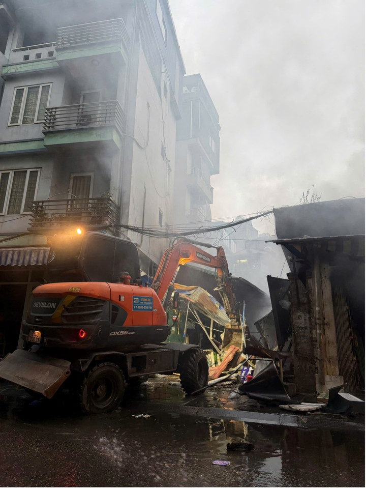Máy xúc được huy động để phá dỡ cấu kiện sụp đổ, mở lối cho cảnh sát tiếp cận dập tắt hoả hoạn.