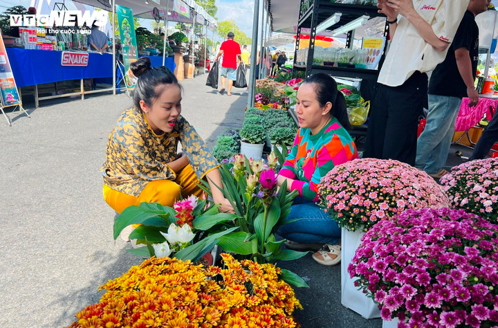 Chị Tính (bên phải) tư vấn cho khách về cách chăm sóc hoa nghệ sen. (Ảnh: Nguyễn Liến)