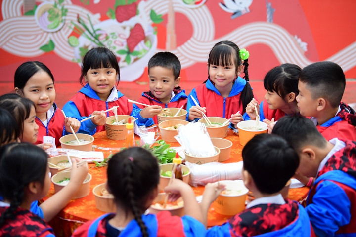 Các em nhỏ vui mừng khi được thưởng thức những tô phở nóng hỏi, thơm ngon. (Nguồn: Báo Tuổi Trẻ)