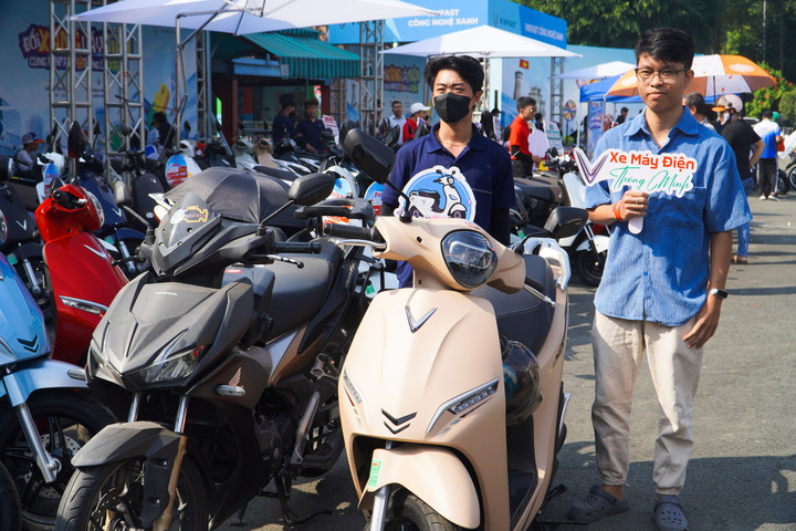 Anh Nguyên (phải) bên chiếc xe máy điện mới của mình