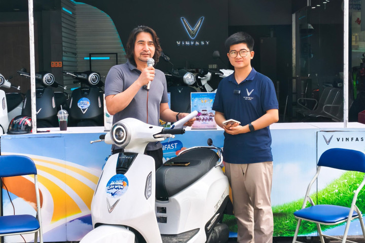 Anh Trịnh Huy Hiệu (bên trái) đang giới thiệu mẫu xe máy điện Evo Grand Lite cho khách hàng.