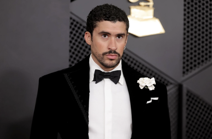 Bad Bunny điển trai trong bộ tuxedo nhung của Schiaparelli với một chút phá cách ở phía sau lưng. Điểm nhấn của outfit là chiếc ghim cài áo hình hoa màu trắng và khăn cài túi được gấp thẳng. (Ảnh: WireImage)