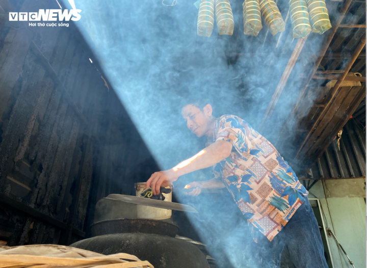 Anh Nguyễn Minh Trị, con út bà Ích, vừa gói bánh tét vừa trông bếp lửa, tiếp nối nghề gia truyền hơn nửa thế kỷ của gia đình.