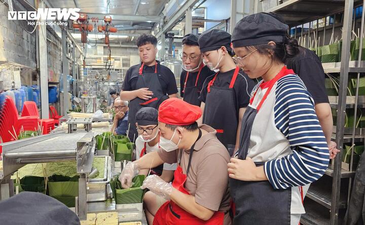 Các bạn trẻ được hướng dẫn các bước gói bánh chưng trước khi tự tay làm.