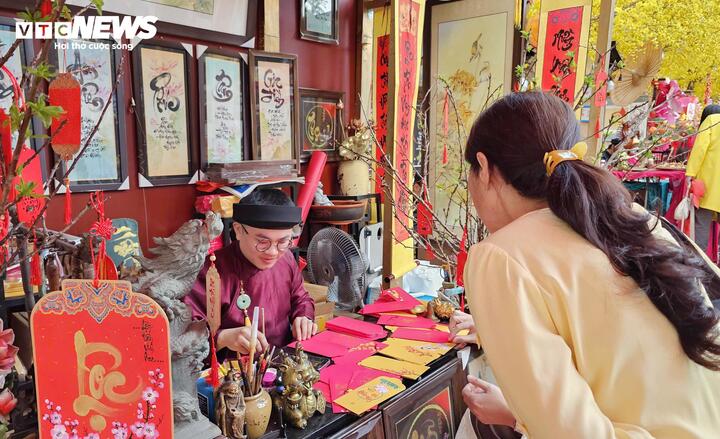 Nghệ nhân thư pháp Võ Minh Mẫn (31 tuổi) lắng nghe câu chuyện của người xin chữ để tìm ra con chữ phù hợp làm “kim chỉ nam” đầu năm.